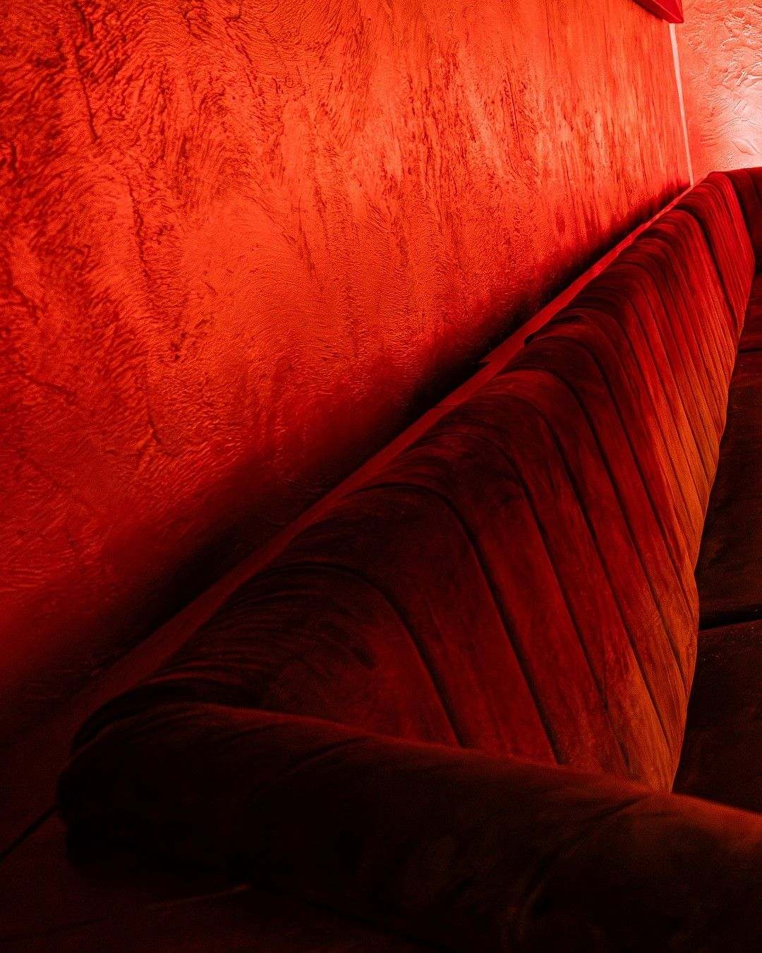 Channel-tufted velvet banquette along the plaster wall